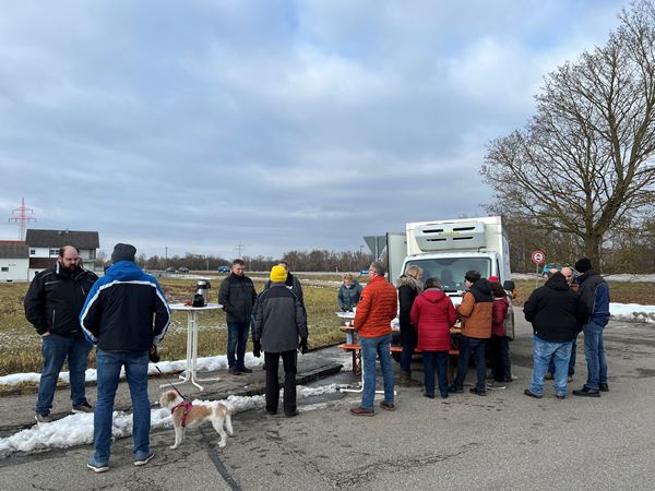 Eine Versammlung von Bürgern an einem Stehtisch und vor dem Tour-Lkw der COMPAKT-Liste Karlskron auf einem verschneiten Platz in Brautlach.