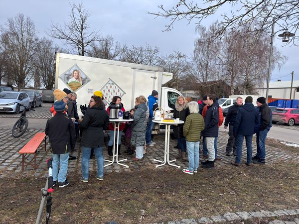 Eine große Menschenmenge versammelt sich um Stehtische vor dem Tour-Lkw der COMPAKT-Liste auf einem gepflasterten Platz in Karlskron.