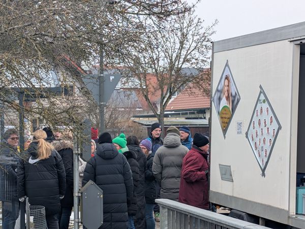 Bürger in warmer Winterkleidung stehen Schlange am Tour-Fahrzeug der COMPAKT-Liste Karlskron in Mändlfeld.