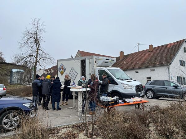 Der COMPAKT-Tour-Lkw parkt vor einem historischen Bauernhaus in Pobenhausen, davor stehen Menschen an einem Infostand.
